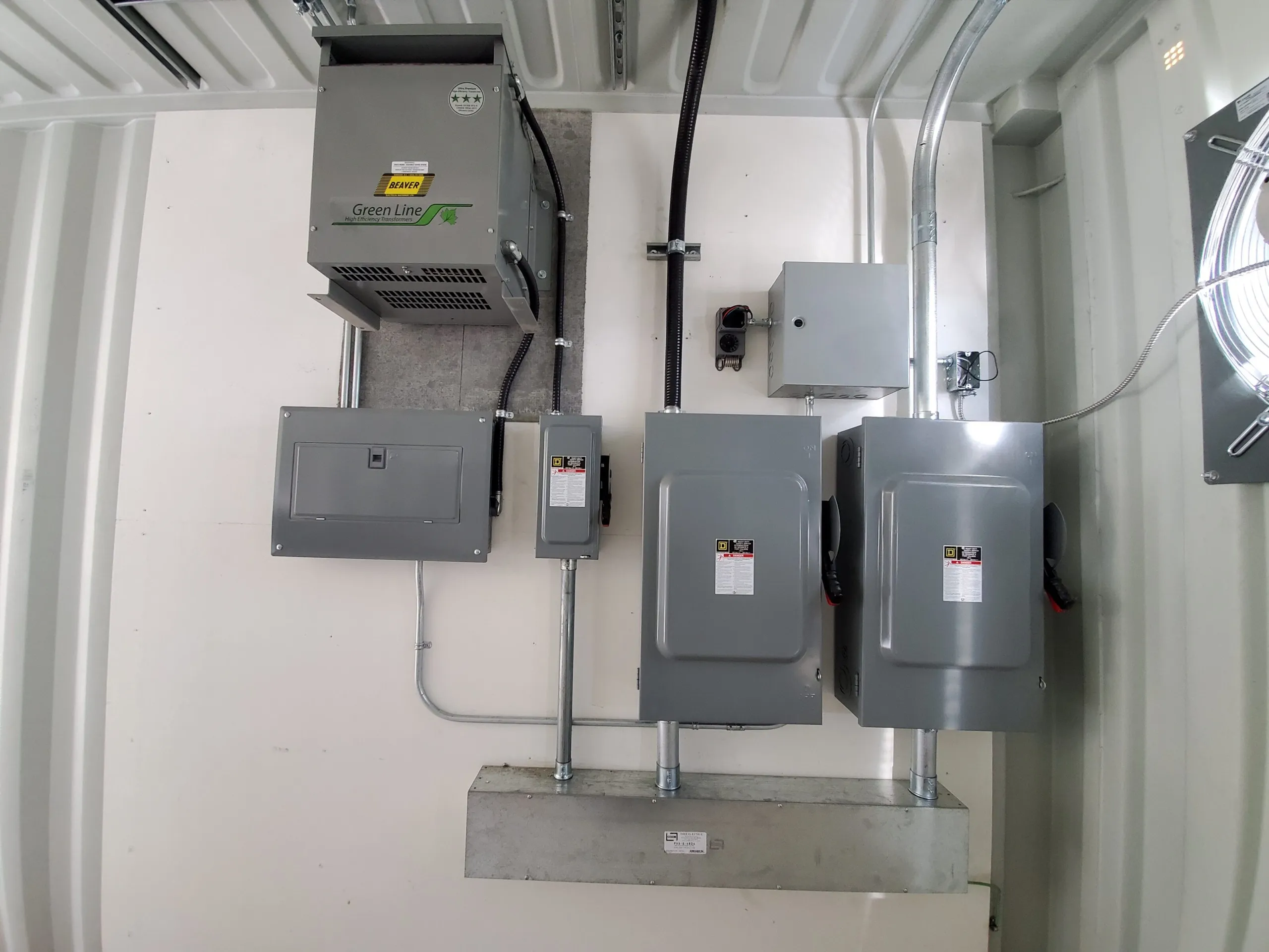 Transformer, panelboard, and disconnect switches installed in an industrial electrical room