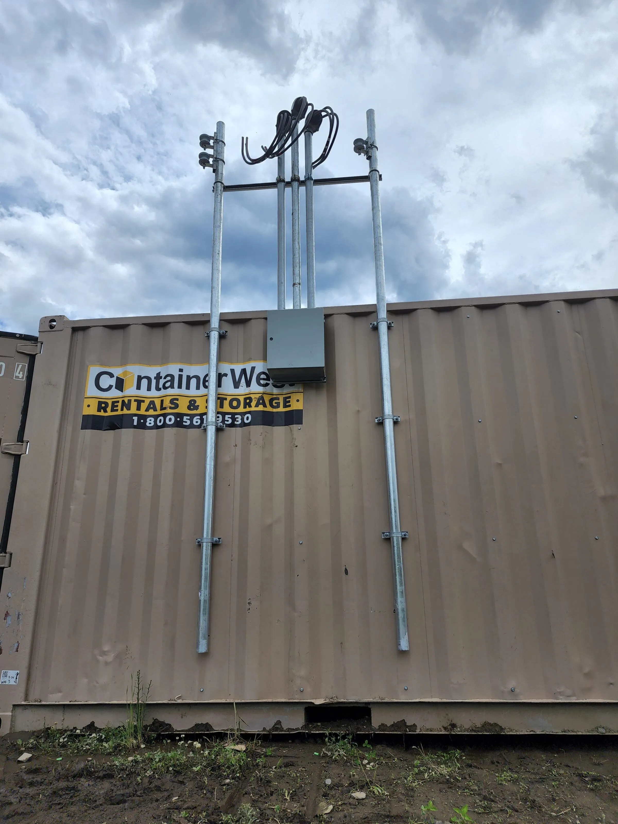 Overhead service masts and junction box installed on a storage container