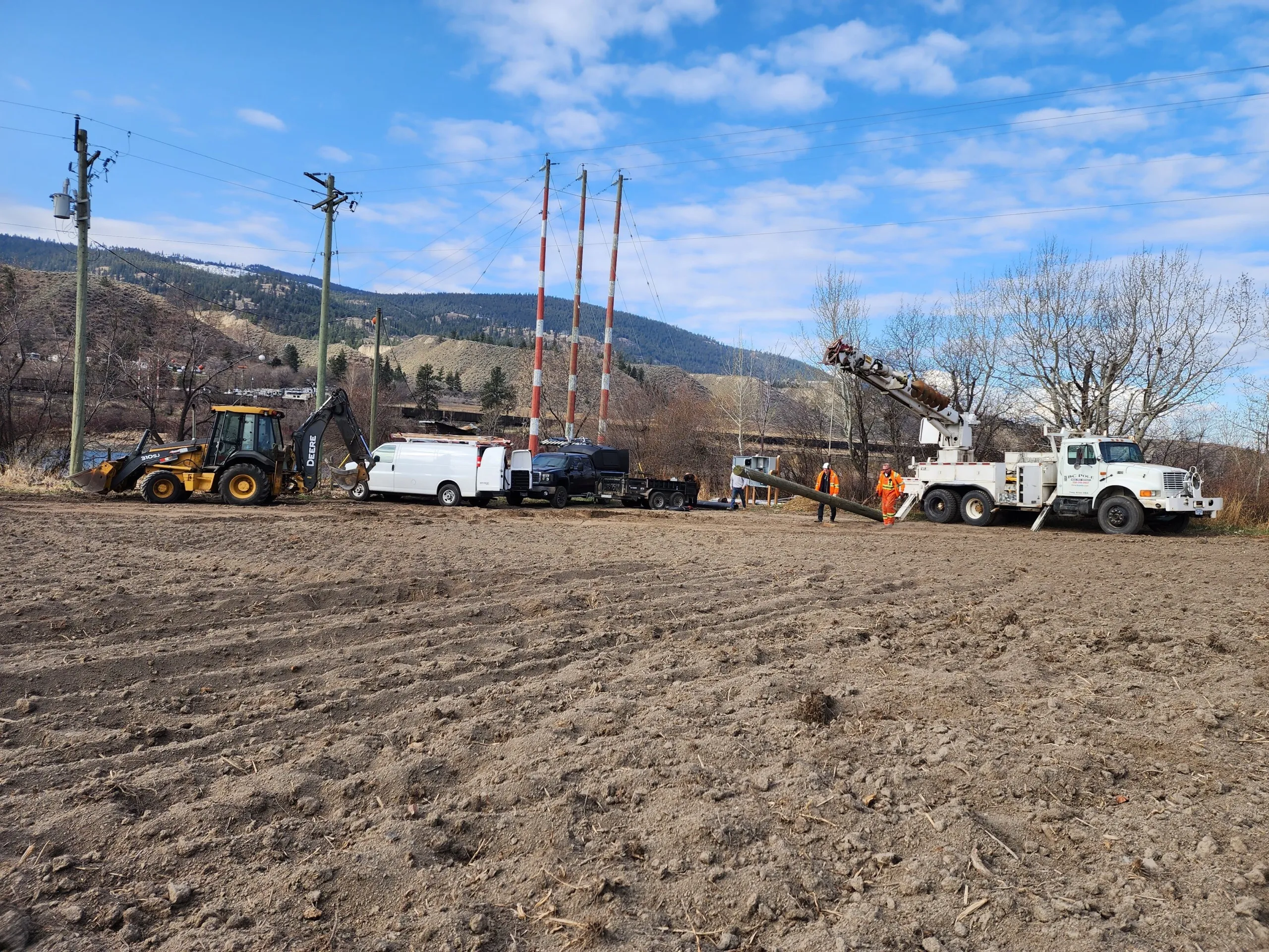 Crew setting a new power pole with a digger derrick for a rural electrical service