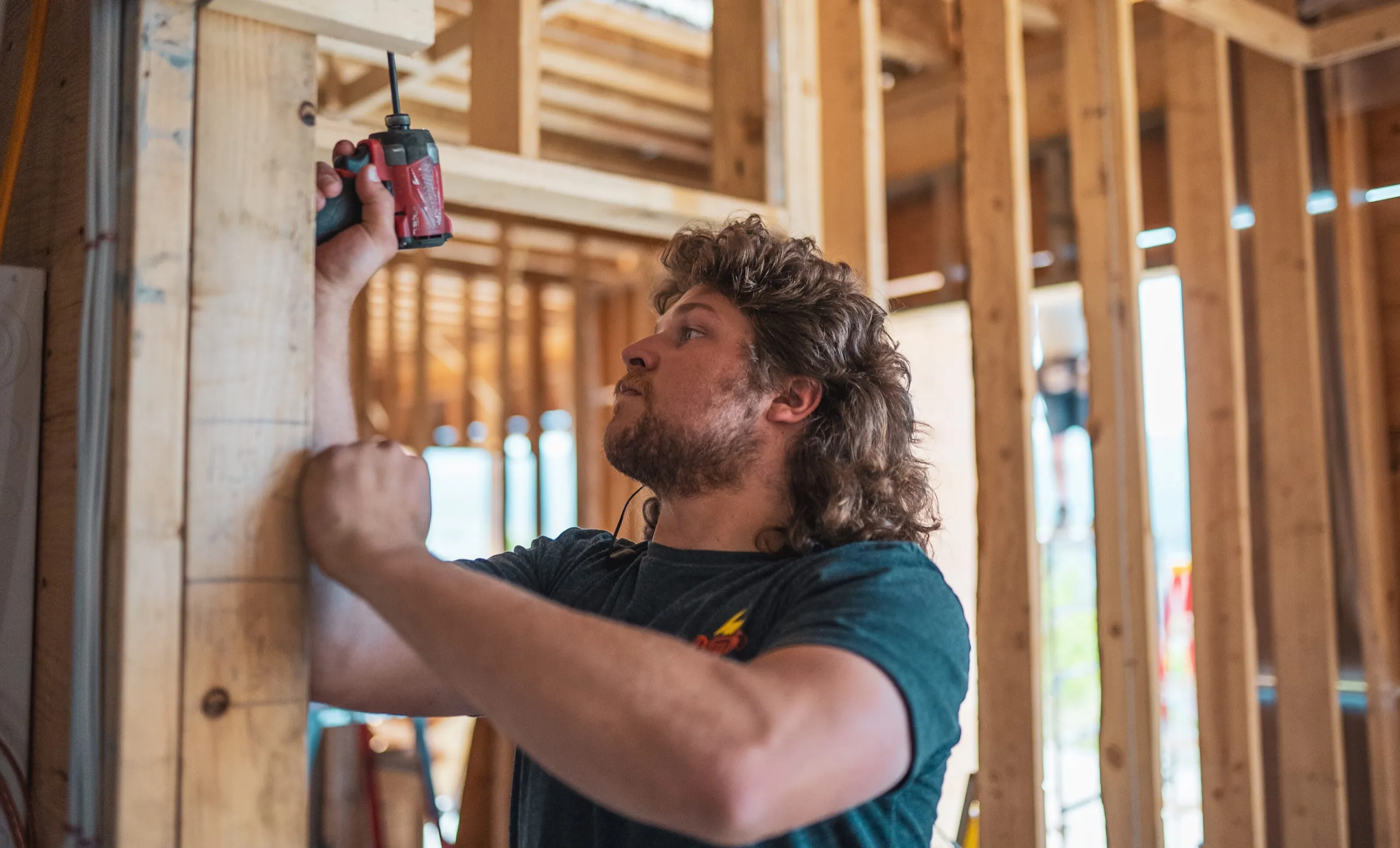 Dayton Power electrician fastening electrical rough-in inside a wood-framed building under construction