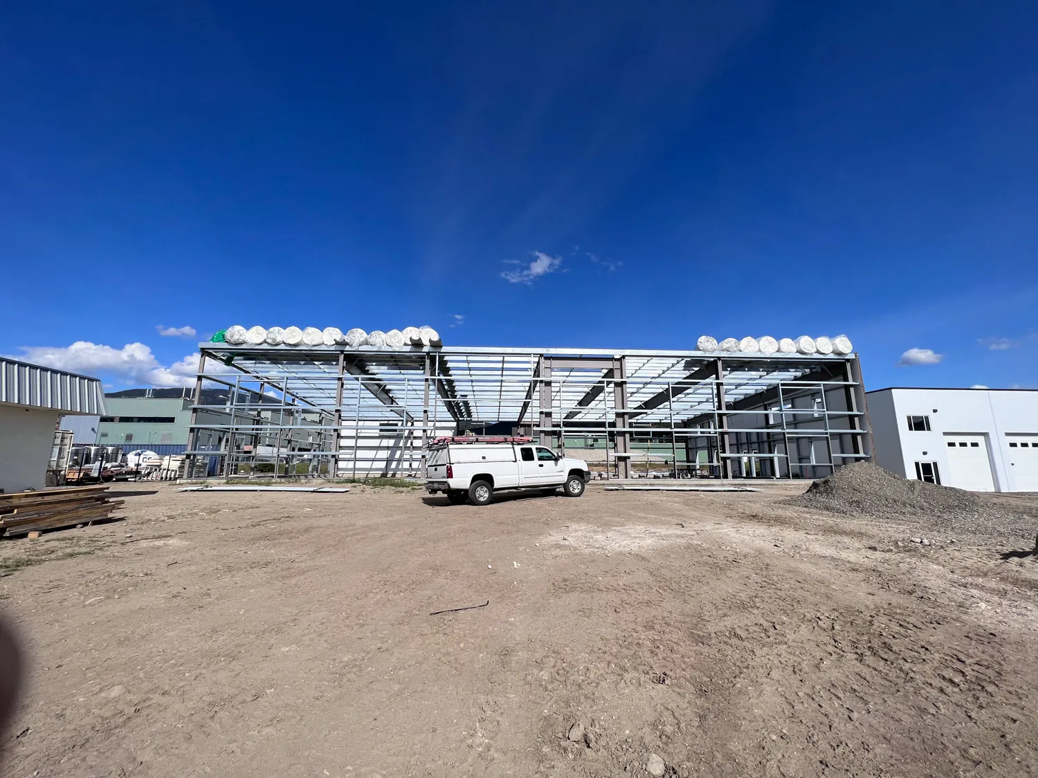 Structural steel framing at a commercial new-construction site with a Dayton service truck