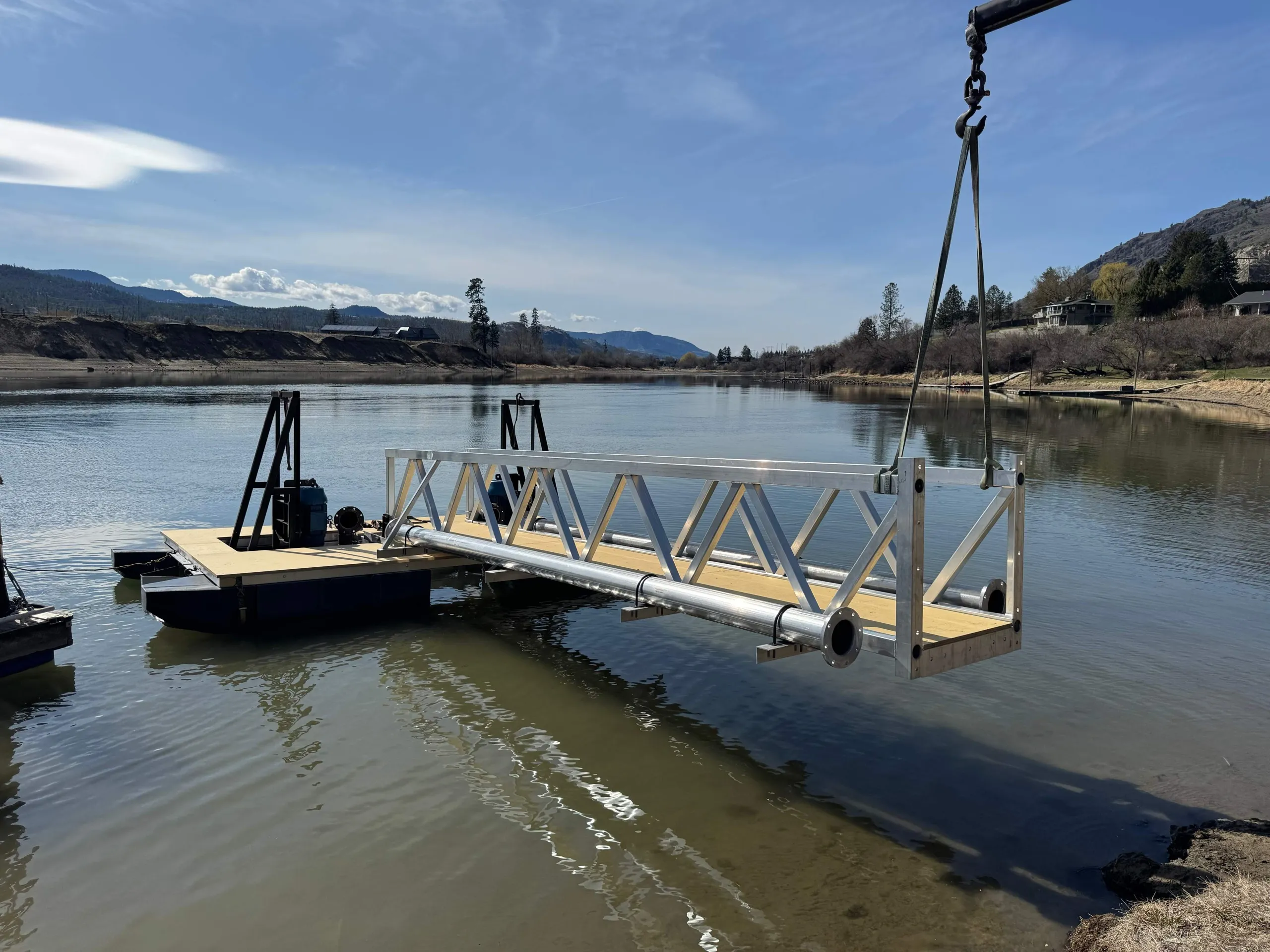 Custom articulating pump dock being craned into the river near Kamloops