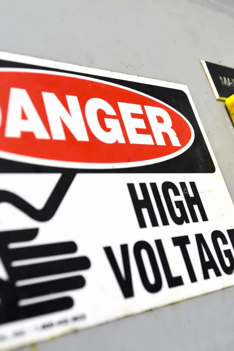 Danger high voltage warning sign beside the main disconnect switch on industrial electrical equipment